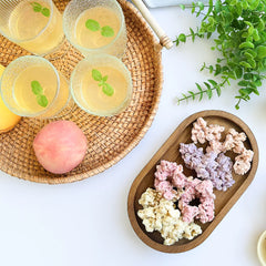 Happy Munch Factory yogurt clusters—assorted fruit flavors on a wooden tray beside iced drinks and a peach, overhead.