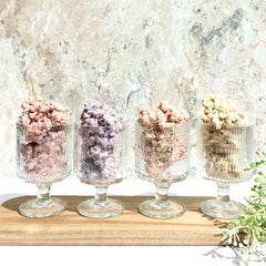 Happy Munch Factory yogurt clusters—four flavors displayed in glass cups on a wooden board.