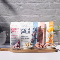 Happy Munch Yogurt cluster packages with samples on a wooden board against a gray textured wall.