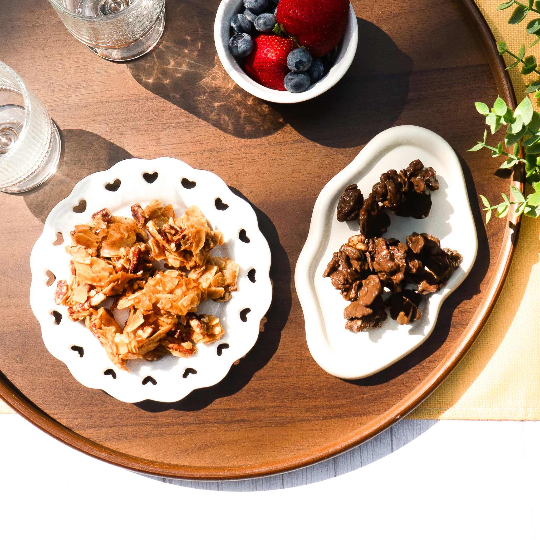 Naked Nuggets and dark choco nuggets on white plates, accompanied by glasses of water and a bowl of berries.