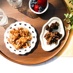 Naked Nuggets and dark choco nuggets on white plates, accompanied by glasses of water and a bowl of berries.