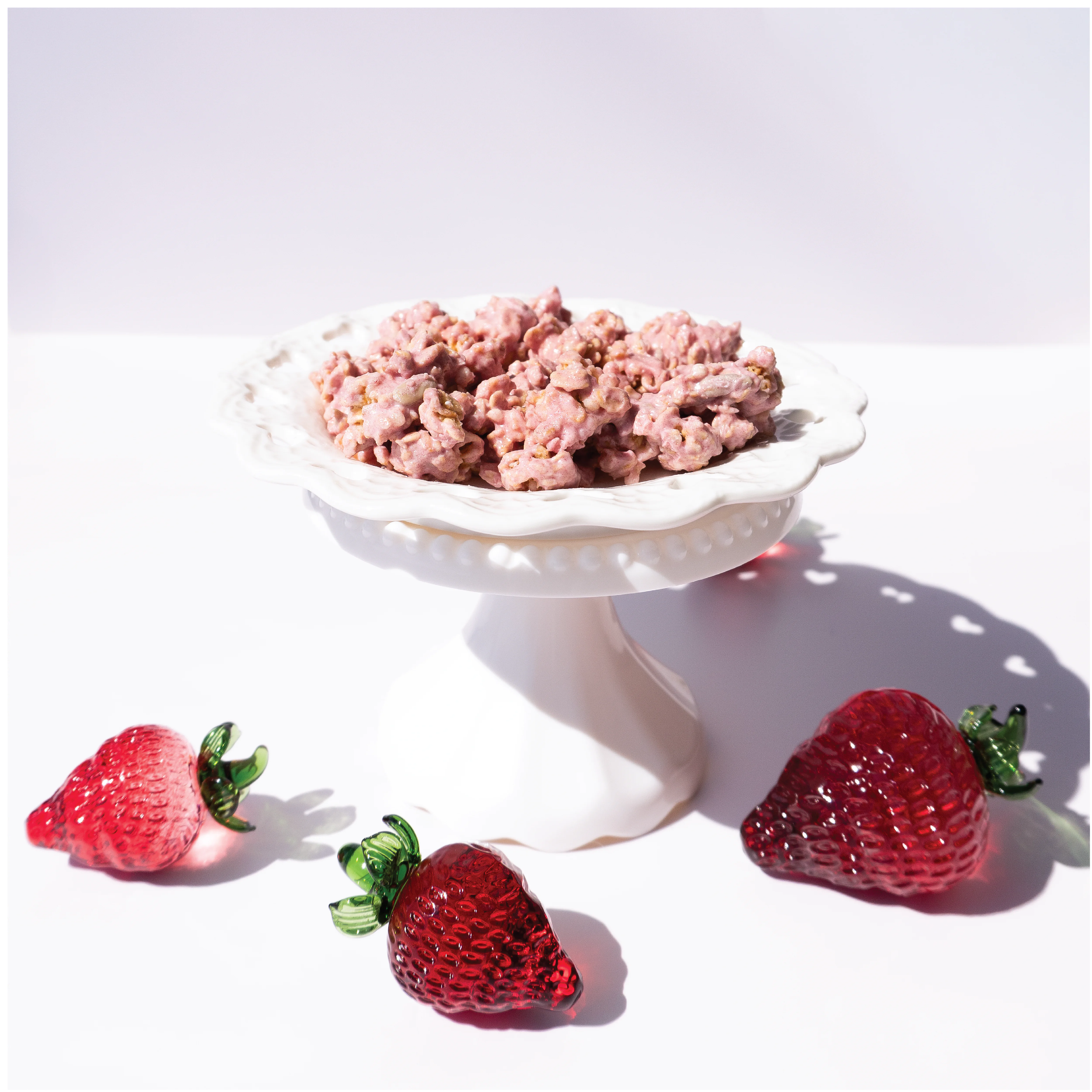 Happy Munch Yogurt Clusters Strawberry Splash in a white bowl with three strawberries on a white background