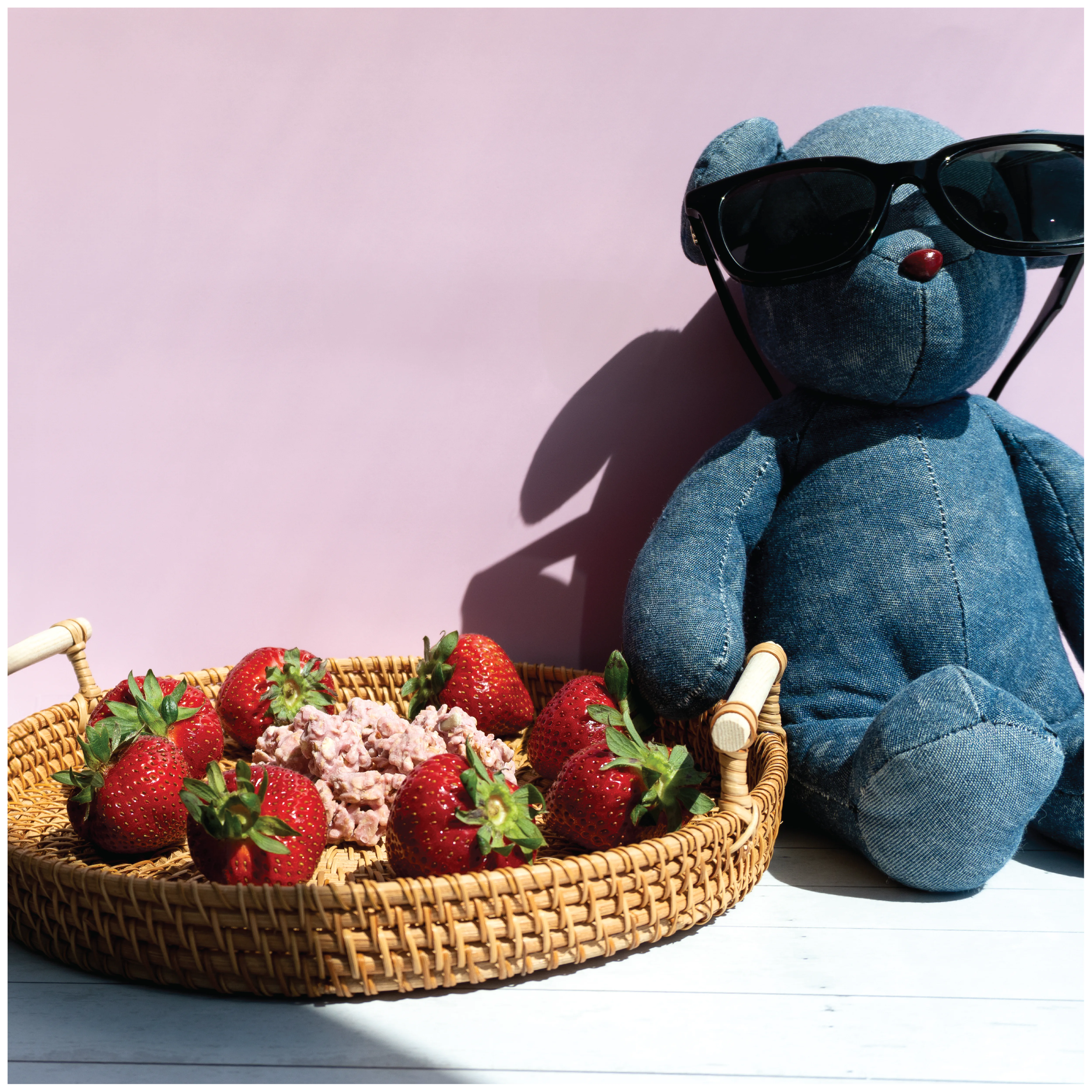 Blue teddy bear with sunglasses next to a basket of strawberries and Happy Munch Strawberry Splash