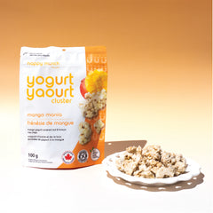Happy Munch Mango Mania yogurt cluster package with a plate of Yogurt Clusters on an orange background